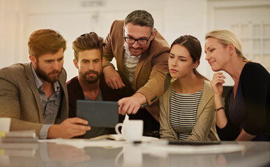 Whats that. Cropped shot of a group of businesspeople looking at a tablet in the boardroom.