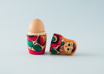 Egg in Russian wooden traditional doll. Minimal Easter concept on a light blue background