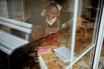 A college girl sitting in cafe and adjusting her hair. Picture taken trough the window.