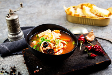 Pan Asian traditional seafood soup with mussels, calamari, mushrooms served with fresh parsley herbs
