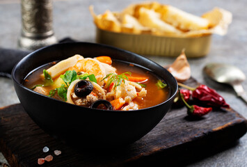 Pan Asian traditional seafood soup with mussels, calamari, mushrooms served with fresh parsley herbs