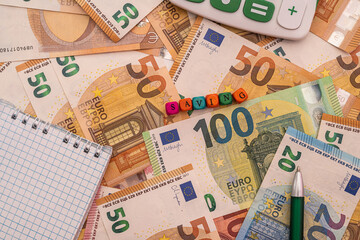 business notebook with pen calculator lie on background with euro banknotes.