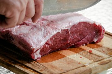 Cutting beef on the table with sharp knife with landscape background.