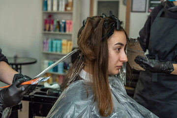 super cool stylist working on the image of a young girl in a beauty salon.