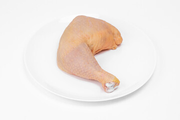 Raw chicken leg quarters on a white ceramic plate, on white background.