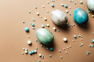 Creative eggs with candy dragees on a brown background. Minimally majestic design for the Easter holiday. Creative concept of colorful eggs and sweets