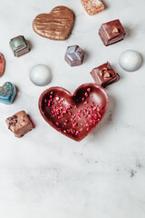 A mix of handmade chocolates on a light background. Creative and stylish heart-shaped chocolate with berries and nuts