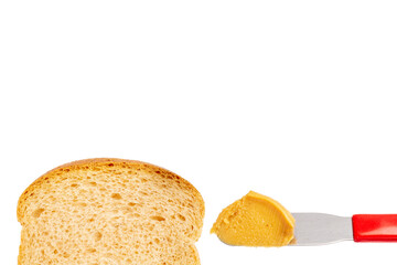 Peanut butter on knife with slice of bread next to it, on white background