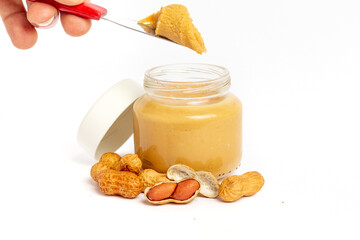 Peanut butter jar on a white background, with scattered peanuts.