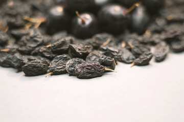blue raisins close-up on a white wooden table with blue grapes on a blurred background