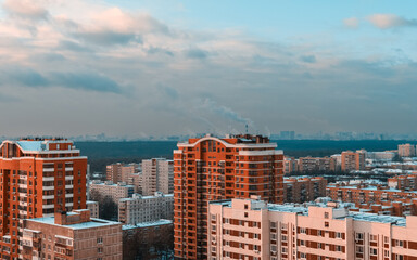 Naklejka premium View of the big city from above. Metropolis under high blue sky with white clouds.