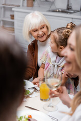 cheerful senior woman hugging granddaughter while celebrating easter with family.