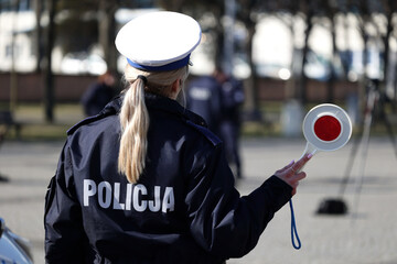 Policjantka drogowa podczas zatrzymywania pojazdów na drodze z tarczą do zatrzymywania w mieście...