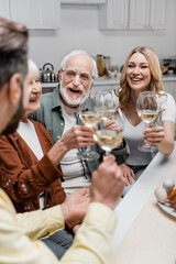 happy senior parents clinking wine glasses with adult son and daughter during easter celebration.