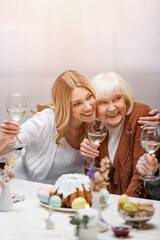 happy mother and daughter with wine glasses embracing during easter dinner.