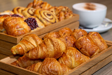 Continental breakfast of assorted pastries including croissants, cinnamon swirls and Danish breakfast pastries served with a cappuccino coffee