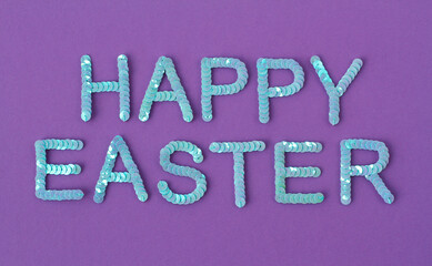 Inscription of "Happy Easter" embroidered with blue sequins on purple textured background as holiday decoration