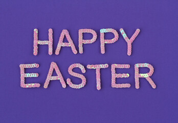 Inscription of "Happy Easter" embroidered with pink sequins on purple textured background as holiday decoration