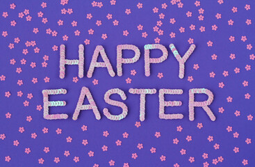 Inscription of "Happy Easter" embroidered with pink sequins on purple textured background with scattered random sequins in form of flowers