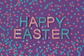 Inscription of "Happy Easter" embroidered with pink and blue sequins on purple textured background with scattered random sequins in form of flowers