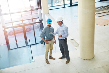 Inspecting the construction site. High angle shot of two businessmen talking in the lobby of their office.