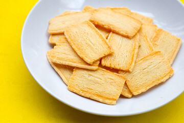 Cheese crispies in plate on yellow background.