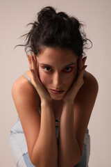 Pretty young woman touches her face posing over white background. Isolated.