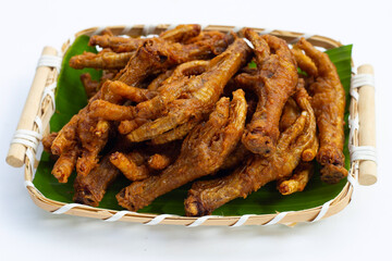 Fried chicken feet in bamboo basket on white background.