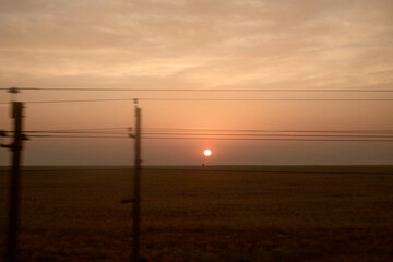View from the train window. Sunrise in the steppe. Railway poles.