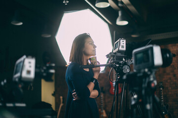 A young female director of photography at work behind a movie camera on a film set for a movie,...