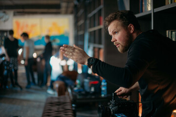 Director of photography with a camera in his hands on the set. Professional videographer at work on filming a movie, commercial or TV series.