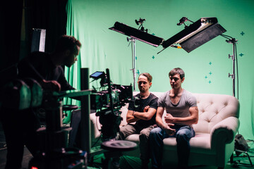 Professional male actors work in the frame on the set. Shooting with actors on a big green chroma key.
