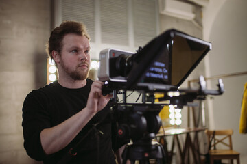 Director of photography with a camera in his hands on the set. Professional videographer at work on filming a movie, commercial or TV series.