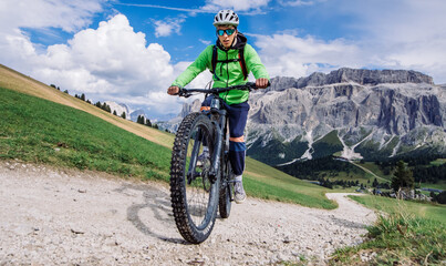 Rower górski, vhłopak jedzie rowerem  elektrycznym ścieżką w górach w Dolomitach . - obrazy, fototapety, plakaty