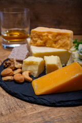 British drinks and food, glasses of Scotch whisky and cheeses collection, blue Stilton, Scottish coloured and English matured cheddar cheeses