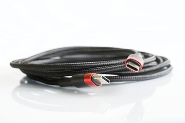 Black braided wire with two red-black usb type-c connectors on a light background. Modern way to connect, transfer data and charge gadgets. Macro. Free space for an inscription