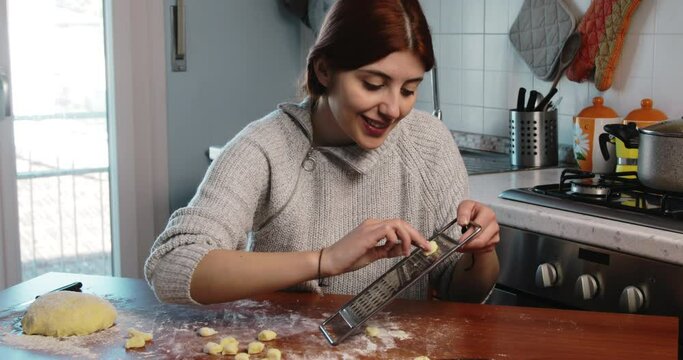 Young girl is stamping homemade little gnocchi on the kitchen table