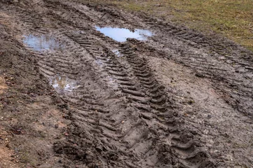 Foto op Plexiglas Close-up of off-road after rain in late autumn after rain. Puddles and tire tracks on country road. Difficulties of movement of people in rural areas © IULIIA GUSEVA