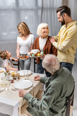 senior woman holding easter cake while serving table for family easter dinner.
