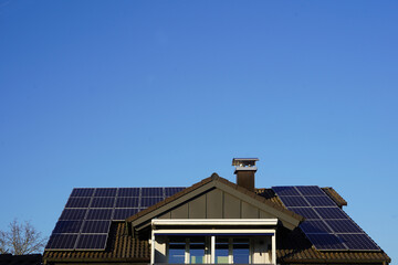 Fototapeta premium Modernes Wohnhaus mit Maximum an Solarpanelen auf dem neuen Dach. Zentral erhebt sich eine grosse Dachgaube. 