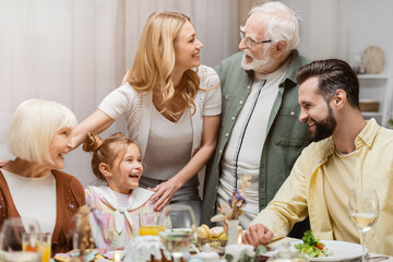senior man talking to smiling woman during easter celebration with family.