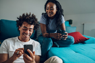 Fototapeta premium African american couple using smartphone while drinking coffee at home