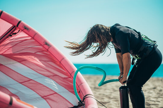 Woman preparing kiteboarding kite with the air pump