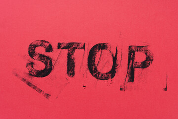 black chalk impression of the word "stop" on pink paper