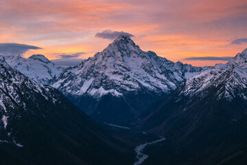 Fantastic view of a high snow-capped mountain at sunset