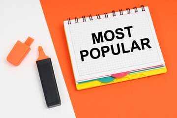 On a white-orange surface lies a marker and a notepad with the inscription - MOST POPULAR