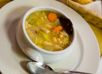 Thick Catalan soup escudella with mix of vegetables, meat and traditional black sausage butifarra. 