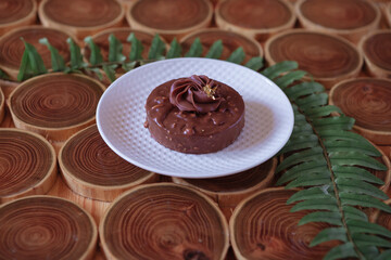 chocolate dessert with filling of caramel, nuts and nougats. The cake is covered with chocolate on a wooded background with a morning natural light