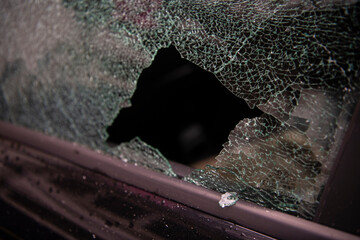 Broken window and abduction of things from a car. A criminal incident. Hacking the car. Broken left side window of a car.