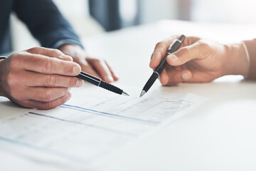 Detailing their success. Cropped shot of two unrecognizable businessmen discussing paperwork at the table in the boardroom.